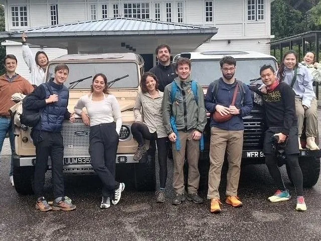 Group of people posing by two vintage Land Rovers