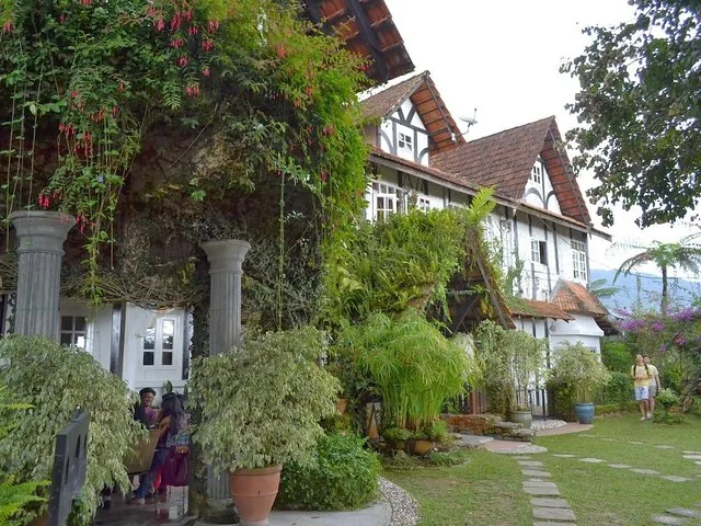 Tudor-style building surrounded by lush green gardens and vines