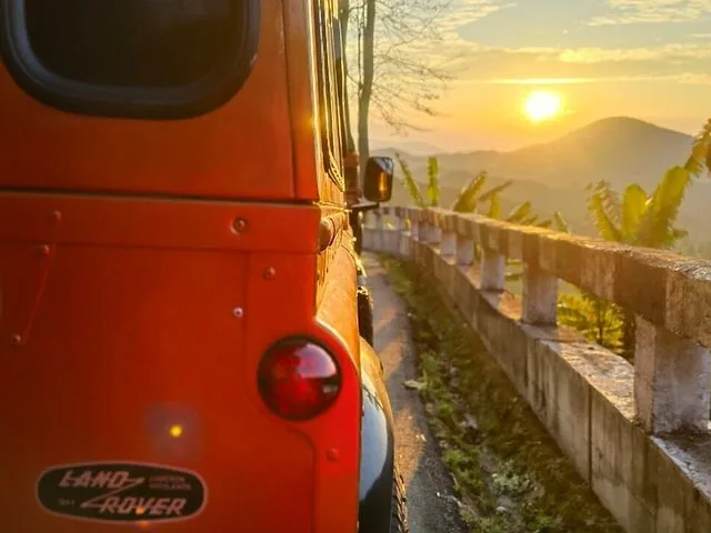 Rear view of an orange Land Rover at sunrise